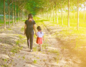 Anya és kislánya sétál az erdőben napkeltekor